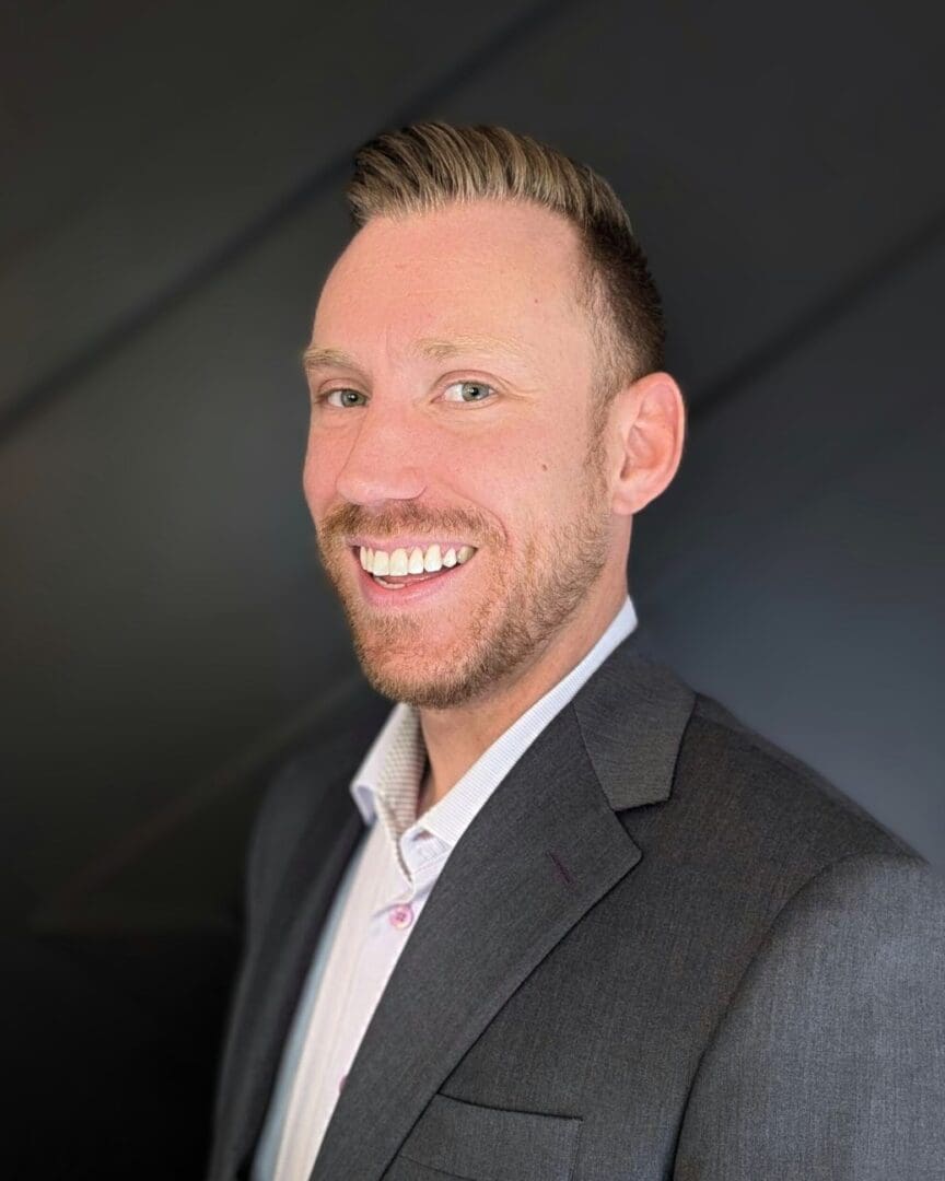 A man in a suit and tie smiling for the camera.